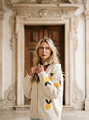 Cream knit button-up cardigan with embroidered yellow lemons and green leaves, worn by a blonde woman.
