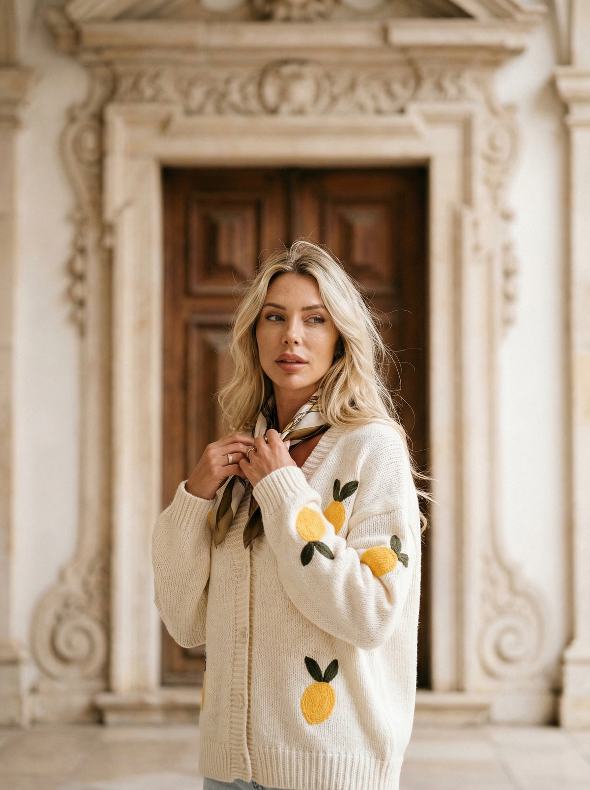 Cream knit button-up cardigan with embroidered yellow lemons and green leaves, worn by a blonde woman.