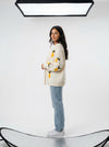 Woman wearing an off-white knit cardigan with yellow lemon appliques and green leaves, paired with light blue jeans.